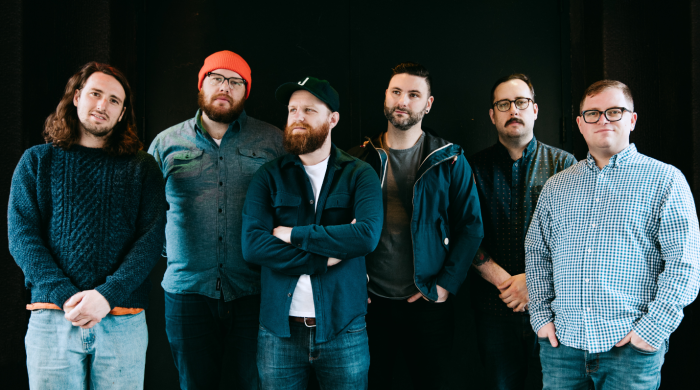 Artist the wonder years standing in front of dark green wall